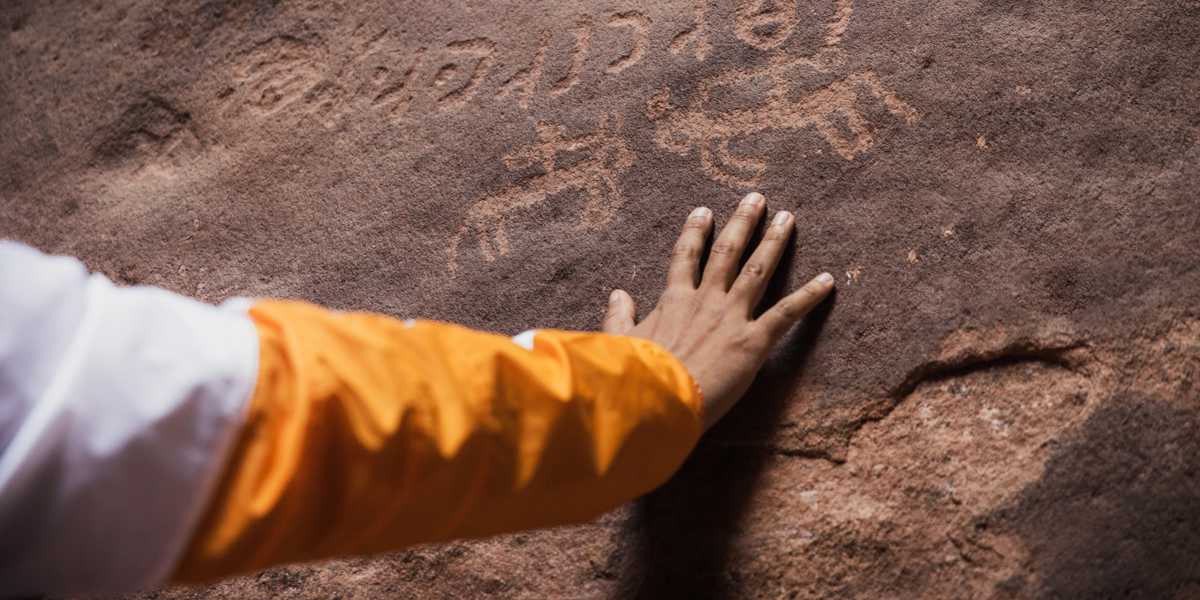 A hand touching some rock inscriptions in Saudi Arabia.